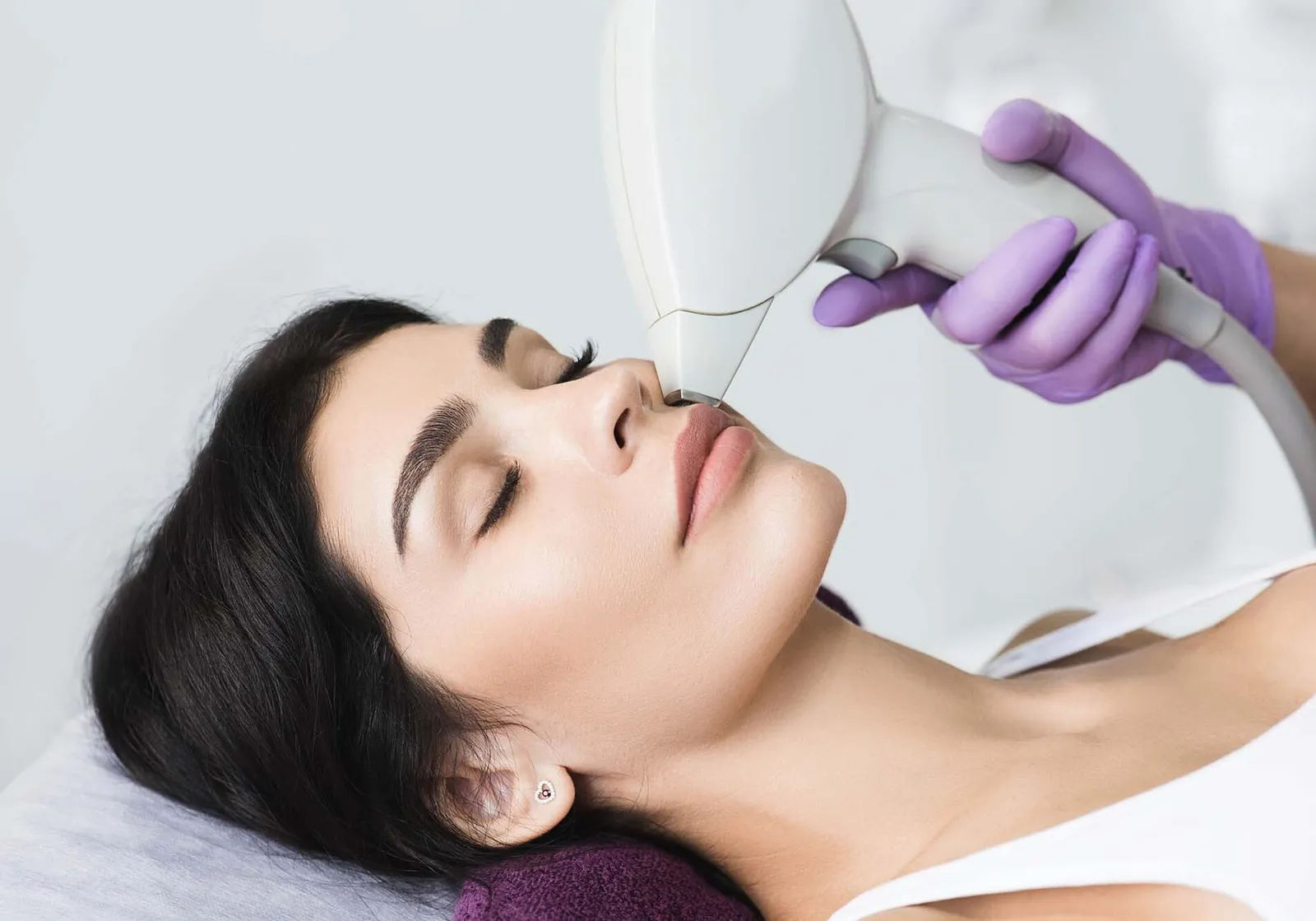 Pretty brunette woman getting hair removing on face. Procedure laser epilation at beauty studio